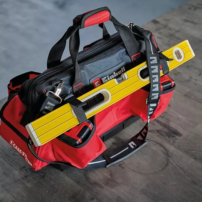 Einhell Werkzeugtasche E-Case - L x B x H: 26,4 x 13,5 x 49 cm, Traglast: 30 kg - Rote und schwarze Einhell-Werkzeugtasche mit gelber Wasserwaage und rotem Messgerät, auf einer Holzoberfläche.