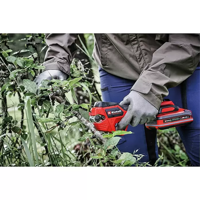 Einhell Professional Akku-Astschere SOLO GP-LS 18/28 - Max. Aststärke: 2,8 mm - Rote und schwarze Einhell elektrische Astschere schneidet einen Ast im Freien, gehalten von einer behandschuhten Hand.