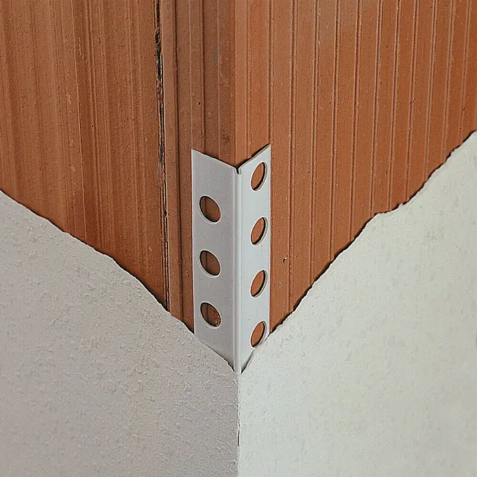 Perfil de yesero de PVC - 2,5 m x 25 mm - Primer plano de un guardacanto blanco con agujeros, sujeto a la esquina de una pared de ladrillo.