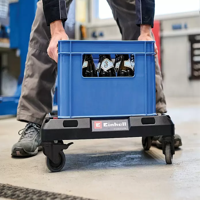 Einhell Transportroller E-Case - L x B x H: 53 x 40 x 11 cm, Kunststoff, Traglast: 120 kg - Person bewegt blaue Kiste mit Flaschen auf schwarzem Einhell E-Case System Transportroller mit Rollen.