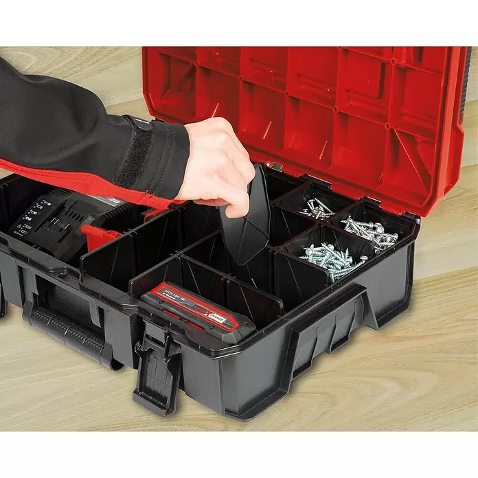 Einhell Aufbewahrungs-Set - Passend für: Einhell E-Case System, 9 Stk. - Eine Hand setzt eine Trennwand in eine schwarz-rote modulare Werkzeugkiste mit Schrauben und einem Akku.