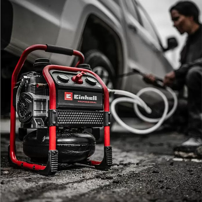 Einhell Professional Power X-Change 18V Akku-Kompressor Silenzzo 18/160 - 18 V, Ohne Akku, 8 bar - Roter und schwarzer Einhell Kompressor mit weißem Schlauch auf Asphalt, zum Reinigen eines weißen Autos.