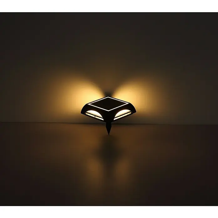 Globo Solar-Außenwandleuchte Wand und Boden - 1,2 W, L x B x H: 14 x 14 x 3,6 cm, IP65, 200 lm, Form: Quadratisch - Das Bild zeigt eine moderne Wandleuchte mit einem einzigartigen Design, die warmes Licht in einem dunklen Raum verbreitet. Die Lampe ist ein stilvolles Dekorationselement.