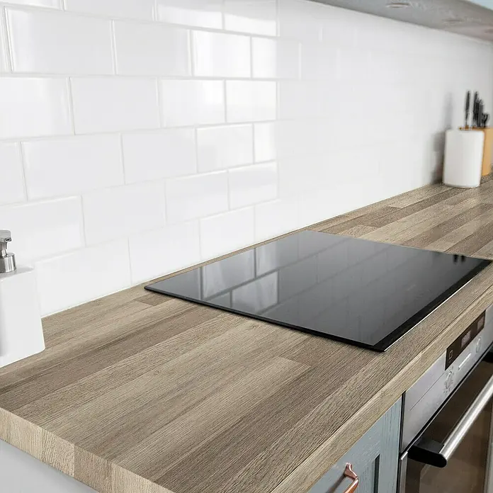 Lámina decorativa autoadhesiva vinílico para encimera - 65 x 200 cm, Lulela nuez - Vitrocerámica encastrada en una cocina moderna con salpicadero de azulejos blancos y encimera de madera. La placa es plana y se integra perfectamente.