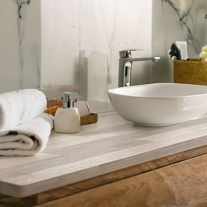 Lámina decorativa autoadhesiva vinílico para encimera - 65 x 200 cm, Lulela class - Lavabo de baño con dispensador de jabón y toallas sobre una superficie de madera, con un fondo marmoleado claro.