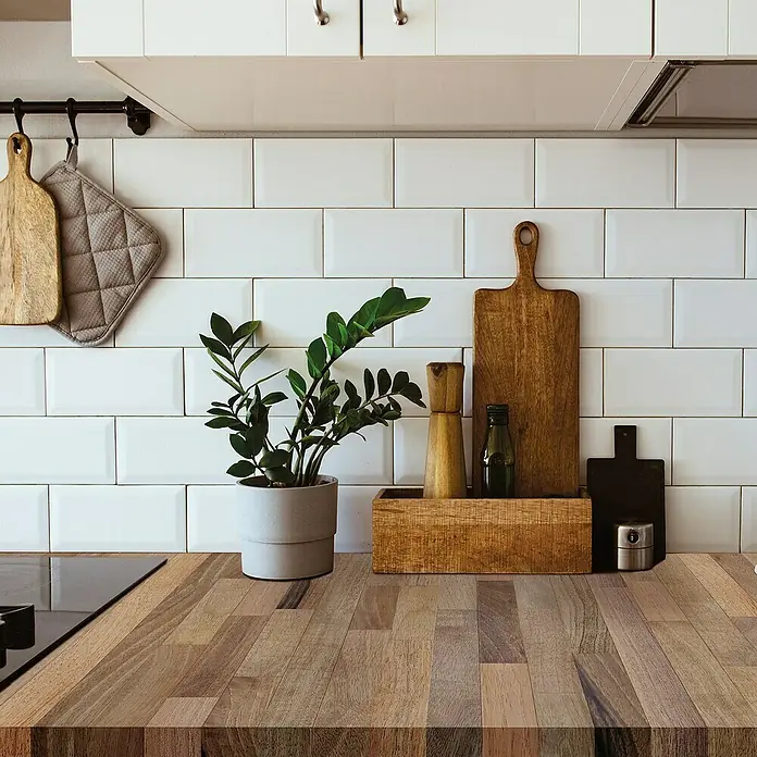 Lámina decorativa autoadhesiva vinílico para encimera - 65 x 200 cm, Triberg - Encimera de cocina con planta en maceta, tablas de cortar y molinillo de especias frente a salpicadero de azulejos blancos.