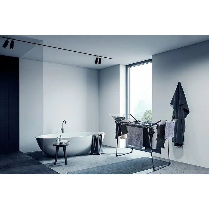 Leifheit Flügel-Wäscheständer Pegasus 180 Solid Black - Länge Wäscheleine: 18 m, Schwarz, B x T x H: 157 x 66 x 87 cm - Wäscheständer im modernen Badezimmer. Der Trockner ist mit grauer Wäsche behangen und passt zum minimalistischen Design des Raumes.