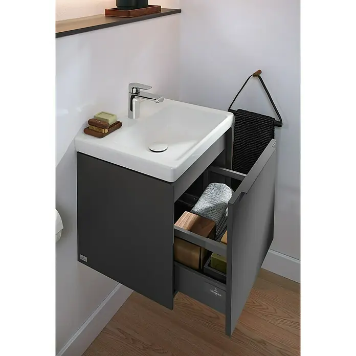 Villeroy & Boch Subway 3.0 Handwaschbecken - 45 x 37 cm, Ohne Spezialglasur, Hahnloch: Mitte, Mit Überlauf, Weiß Alpin, Ungeschliffen, Rechteckig - Das Bild zeigt einen modernen Waschbeckenunterschrank mit Auszug, der Handtücher und Badutensilien stilvoll verstaut.