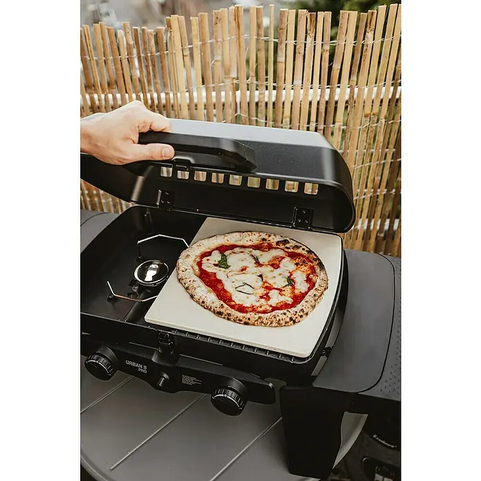 Enders Pizzastein - Cordierit, Passend für: Enders Urban II- und Explorer II-Serie - Schwarzer tragbarer Pizzaofen (URBAN II PRO) mit frisch gebackener Margherita-Pizza auf Pizzastein. Eine Hand öffnet den Deckel.