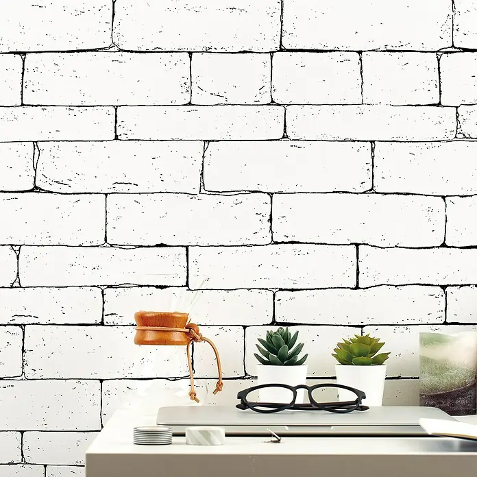 Lámina decorativa autoadhesiva vinílico Premium - 90 x 280 cm, Outline, Blanco - Un espacio de trabajo moderno con plantas, gafas, cafetera y computadora portátil frente a una pared de ladrillo blanco.