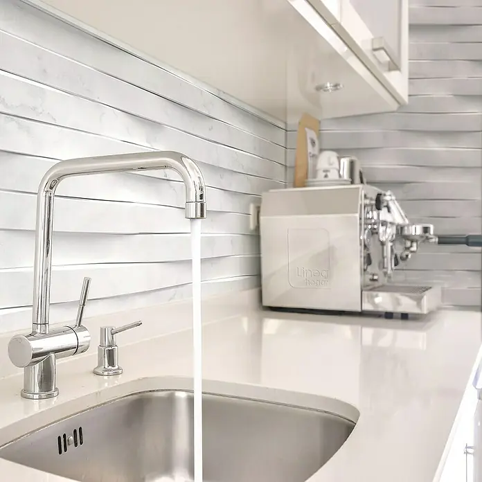 Papel pintado de vinilo autoadhesivo Carrara - Blanco, L x An: 280 x 65 cm - Elegante grifo de cocina de acero inoxidable con agua corriente en una cocina moderna con azulejos de mármol blanco y máquina de café espresso.