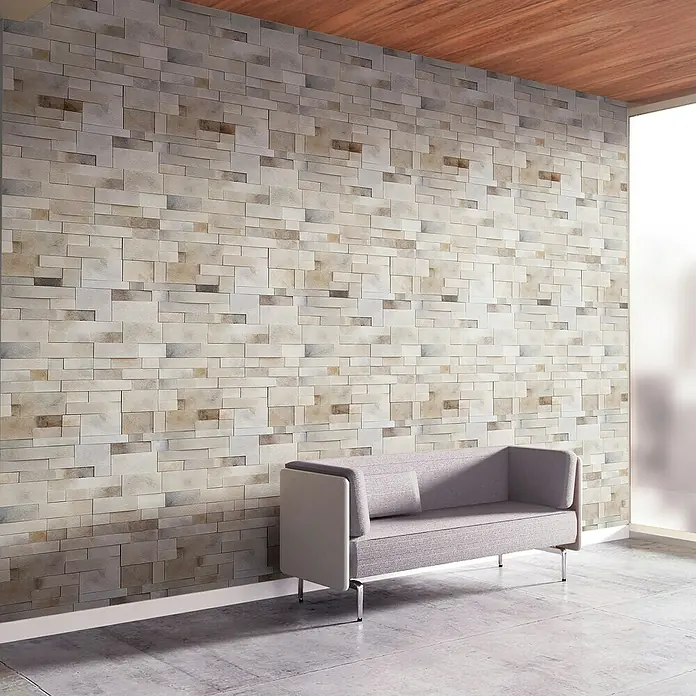 Papel pintado de vinilo autoadhesivo Paros - Beige, L x An: 280 x 65 cm - Elegante sofá gris frente a una pared de piedra texturizada, combinando diseño moderno y confort. Un atractivo punto focal para espacios habitables.