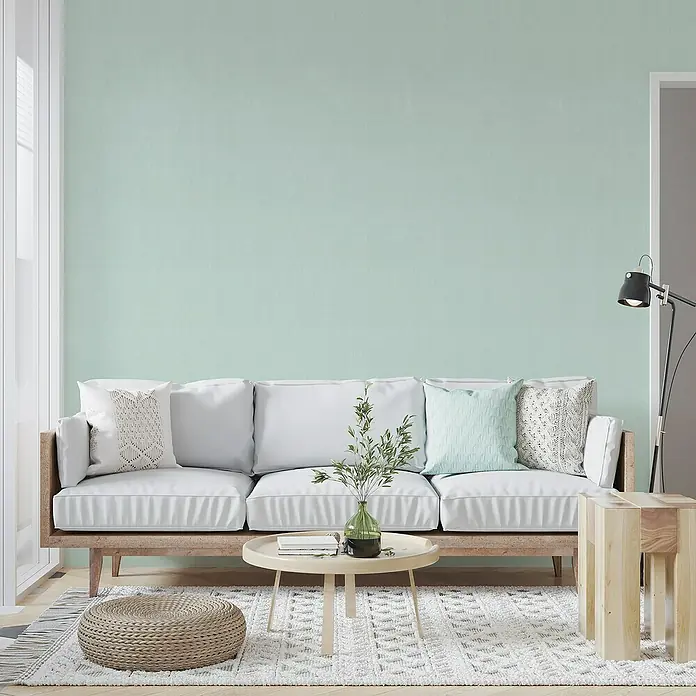 Papel pintado de vinilo autoadhesivo Prato - Turquesa, L x An: 280 x 65 cm - Salón con pared verde menta, sofá con cojines, mesa de centro con decoración y lámpara de pie. La decoración es moderna y acogedora.