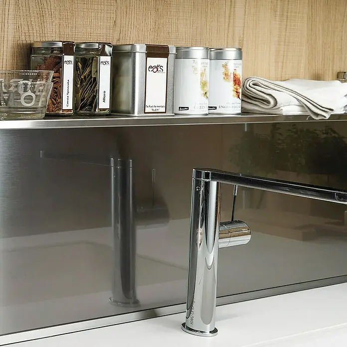 Lámina para ventana de vinilo Aluminium - 60 cm x 2 m, Plateado - Primer plano de un grifo de cocina y recipientes de especias. El grifo brilla en primer plano, mientras que las especias están en la estantería del fondo.