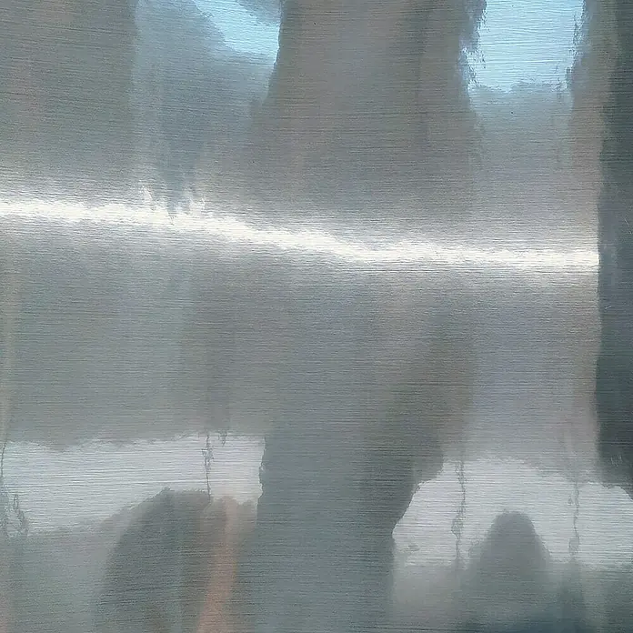 Lámina para ventana de vinilo Aluminium - 60 cm x 2 m, Plateado - Primer plano de una superficie de metal cepillado que muestra reflejos y detalles sutiles de textura.