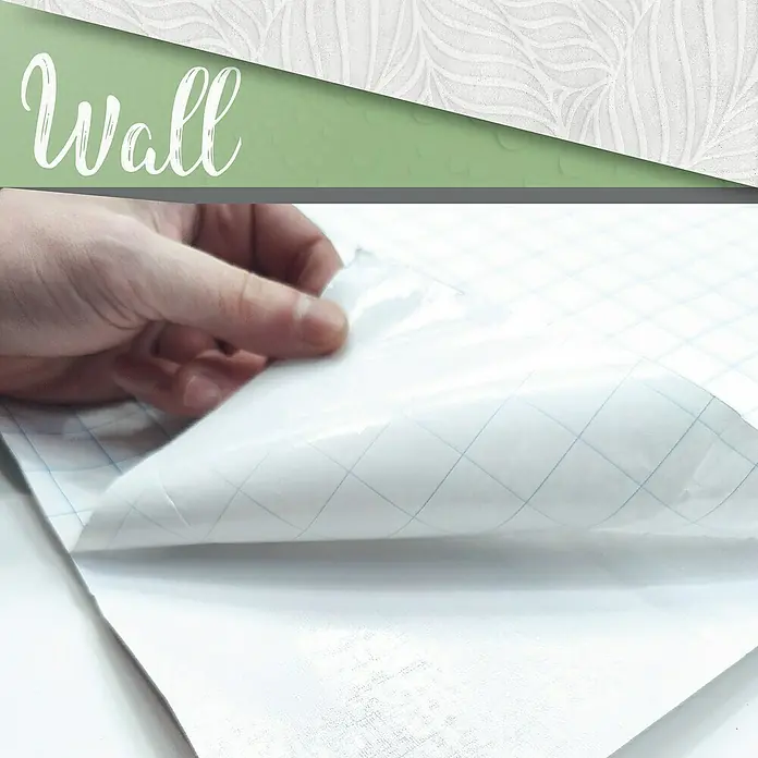 Papel pintado de vinilo autoadhesivo Ojaldre - Gris, L x An: 280 x 65 cm - Primer plano de una mano que despega la capa protectora de un film de pared blanco autoadhesivo con líneas de cuadrícula, resaltando su fácil aplicación.