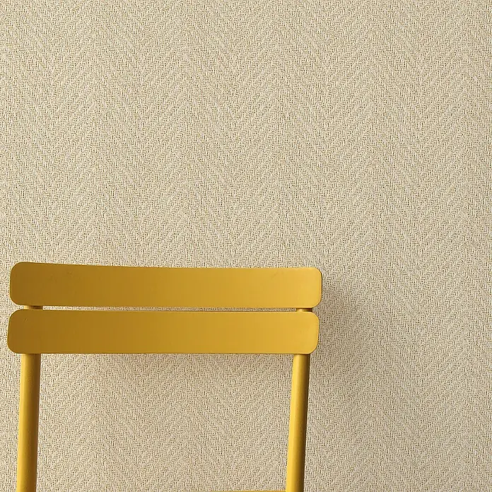 Lámina decorativa autoadhesiva vinílico Premium - 90 x 280 cm, Cima clara, Beige - Silla amarilla sobre un fondo de espiga beige. La silla presenta un diseño sencillo y está situada delante de un revestimiento de pared texturizado.