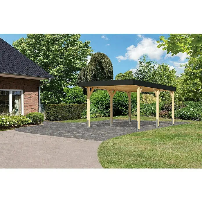 Karibu Carport 1 - Außenmaß inkl. Dachüberstand (B x T): 3,18 x 5,76 m, Naturbelassen - Das Bild zeigt einen Holzcarport mit einem schwarzen Dach auf einem gepflasterten Bereich neben einem Rasen und Bäumen.