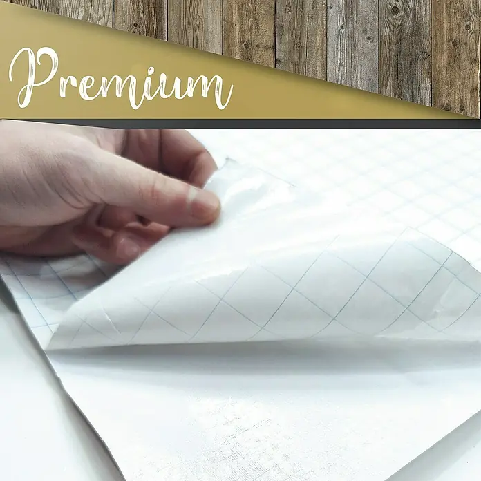 Lámina decorativa autoadhesiva vinílico Premium - 90 x 280 cm, Tablón viejo, Marrón - Primer plano de una mano que despega una esquina de una película autoadhesiva premium con líneas de cuadrícula, ideal para manualidades y decoración.