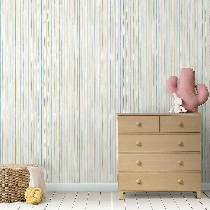 Lámina decorativa autoadhesiva vinílico Premium - 90 x 280 cm, Pastel, Multicolor - Una habitación infantil luminosa con papel pintado a rayas, una cómoda de madera clara y accesorios decorativos como una cesta y un cojín de cactus.
