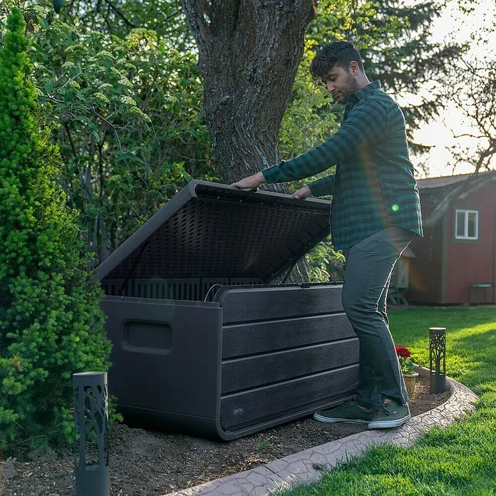 Aufbewahrungsbox Space L - B x T x H: 147,1 x 72 x 63,6 cm, Kunststoff, Anthrazit - Mann öffnet eine dunkelgraue, holzgemusterte Outdoor-Aufbewahrungsbox im Garten.