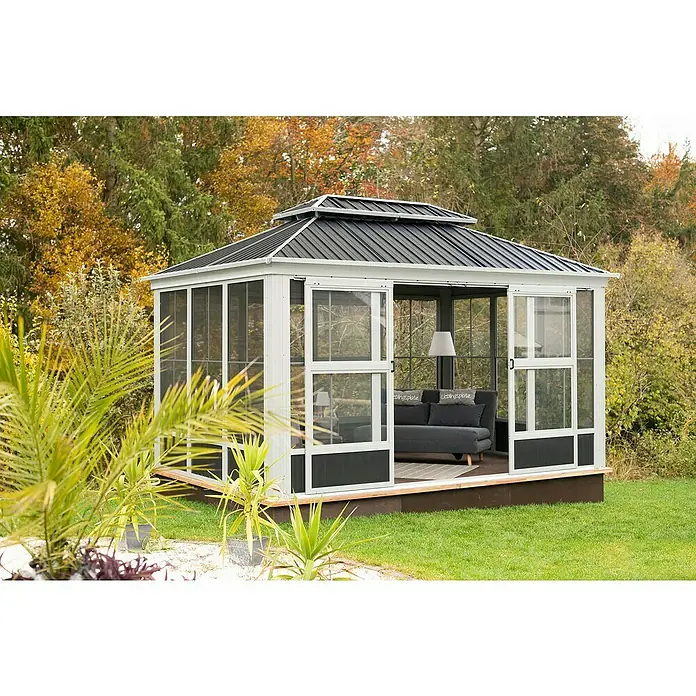Sojag Standard-Pavillon Olan 1014 - Anthrazit, Aluminium, B x T: 311,1 x 435,6 cm - Ein weiß umrahmter Pavillon mit dunkelgrauem Metalldach und Insektenschutzwänden steht in einem Garten, eingerichtet mit einem grauen Sofa und Lampe.