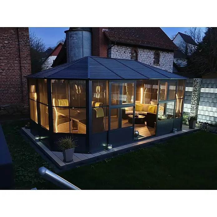 Sojag Standard-Pavillon Charleston 1212 - B x T: 383,6 mm x 383,6 cm, Anthrazit, Aluminium - Beleuchteter, dunkelgrauer Gartenpavillon mit geriffeltem Dach, durchsichtigen Paneelen und Sitzgelegenheiten im Inneren bei Dämmerung.