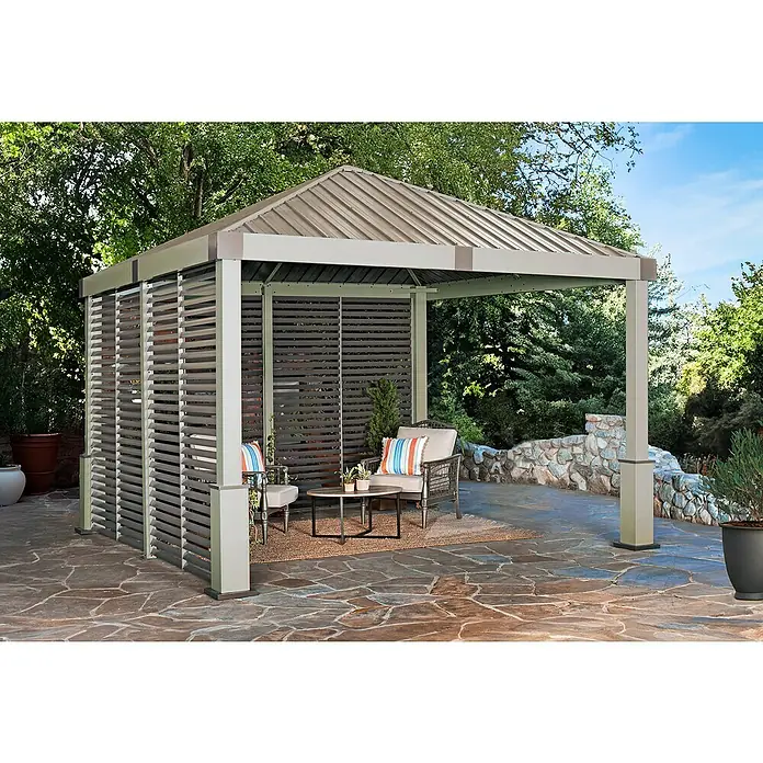 Sojag Standard-Pavillon Nanda 1212 - B x T: 363 x 363 cm, Champagner, Aluminium - Modernes Metallpavillon mit braunem Dach und Lamellenwänden bietet schattige Sitzgelegenheiten auf einer Steinterrasse.