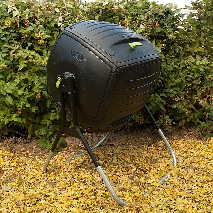 Lifetime Komposter Premium - 189 l, 75 x 77 x 112 cm - Ein schwarzer Lifetime-Komposter mit grünen Akzenten steht im Garten, umgeben von Blättern und Büschen. Praktisch für die Gartenarbeit.