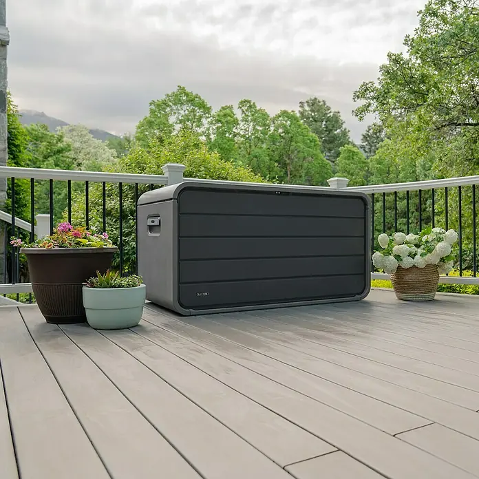 Aufbewahrungsbox Space XL - B x T x H: 146,7 x 72,4 x 77,2 cm, Kunststoff, Anthrazit - Dunkelgraue Outdoor-Aufbewahrungsbox auf hellgrauer Holzterrasse, umgeben von Topfpflanzen.
