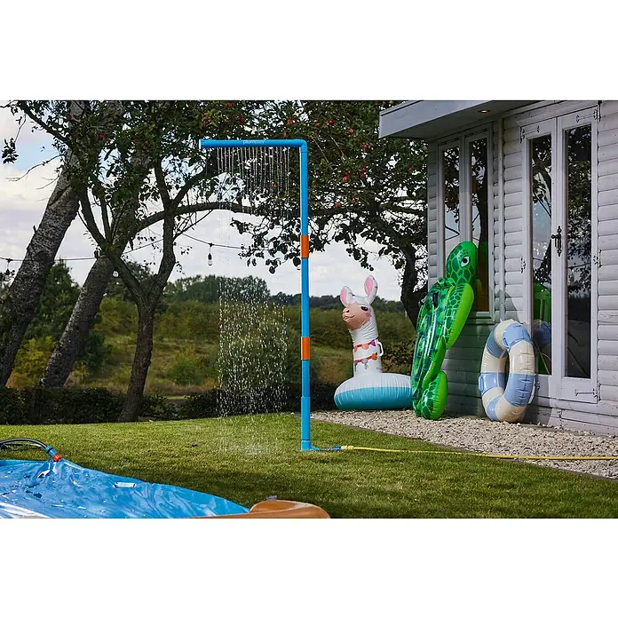 Plum Kinderspielturm Water Park Wasservorhang - Blau - Blaue und orangefarbene Außendusche sprüht Wasser in einem sonnigen Garten, mit aufblasbaren Spielzeugen.