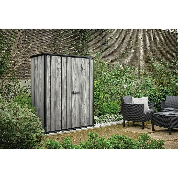 Keter Geräteschrank Signature Strom Grey High-Store - Außenmaß inkl. Dachüberstand (B x T): 140 x 73,6 cm, Stormgrey, Kunststoff - Hoher, schmaler Gartenschrank in heller Holzoptik mit schwarzem Rahmen, in einem Garten mit Sitzgelegenheiten.