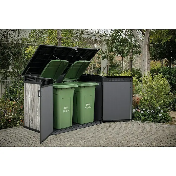 Keter Garten-Aufbewahrungsbox Signature Storm Grey Grande-Store - Außenmaß inkl. Dachüberstand (B x T): 190 x 109 cm, Kunststoff, Stormgrey - Outdoor-Mülltonnenbox mit heller Holzstruktur und dunkelgrauen Paneelen, beherbergt zwei große grüne Mülltonnen mit offenen Deckeln, in einem gepflasterten Garten.