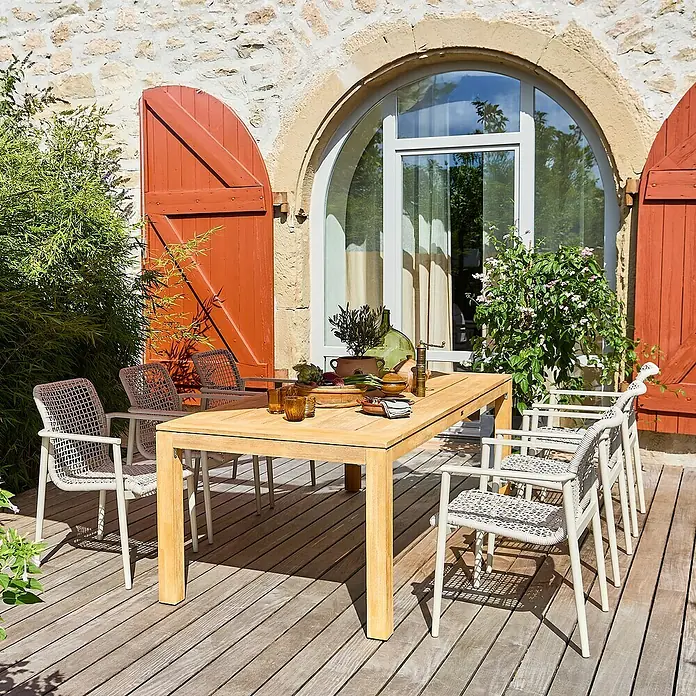 Gartenmöbel-Set Laura/Solo - 7 -tlg., Braun/Light-Greige, Stapelbar - Ein einladender Außenbereich mit einem hellen Holztisch und weißen Stühlen, ideal für Mahlzeiten im Freien.