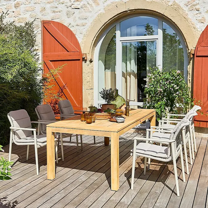 Sunfun Gartenmöbel-Set Laura/Solo - 13 -tlg., Braun/Leight-Greige, Stapelbar - Bild eines Gartentisches mit Stühlen auf einer Holzterrasse, umgeben von üppigem Grün. Der Tisch ist mit Speisen und Getränken gedeckt.