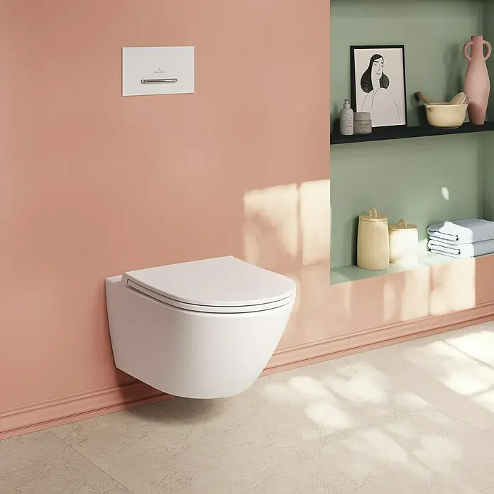Villeroy & Boch Subway 3.0 Wand-WC - Spülrandlos, Mit antibakterieller Glasur, Spülform: Tief, WC Abgang: Waagerecht, Weiß Alpin - Weißes wandhängendes WC in einem modernen Badezimmer mit pfirsichfarbenen Wänden und grünen Regalen.