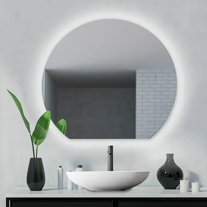 Camargue Espejo con luz Duved - Diámetro: 60 cm, Plateado - Un espejo redondo iluminado cuelga sobre un lavabo moderno y un grifo, flanqueado por un jarrón, dispensadores de jabón y velas en un tocador.