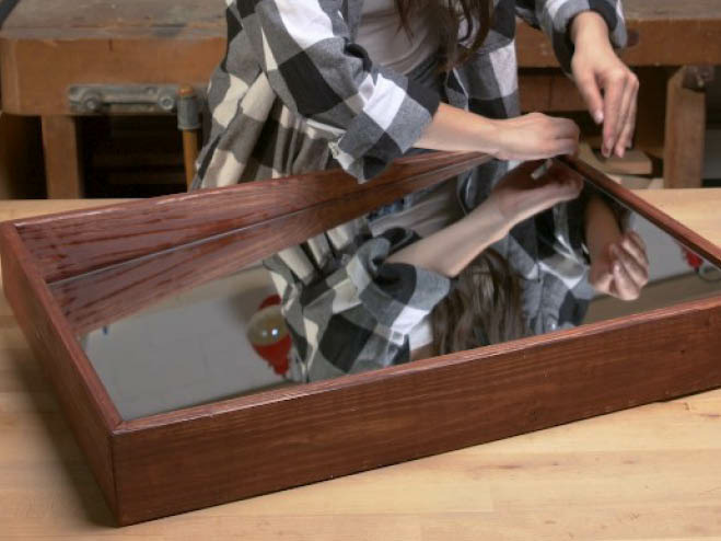 Ein Spiegel ohne Rahmen wird in den DIY Regalrahmen aus Holz gelegt