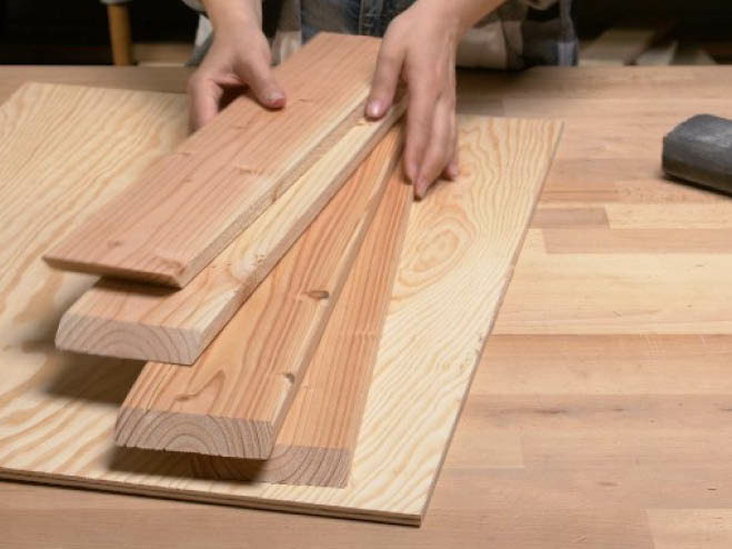 1 Holzplatte und 4 Holzbretter liegen auf einer Werkbank bereit für die weitere Verarbeitung 