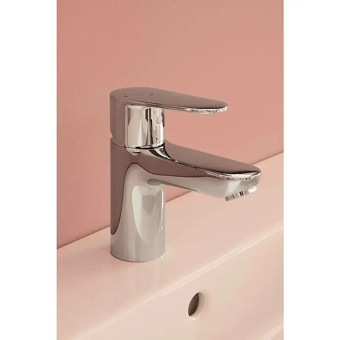 Roca Mitos Plus Grifo de lavabo - Cromo, Brillante - Grifo cromado brillante sobre un lavabo rosa, mostrando un diseño moderno y elegante para accesorios de baño.