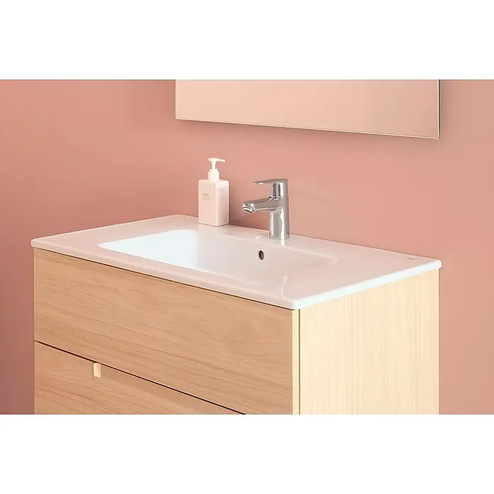 Roca Mitos Plus Grifo de lavabo - Cromo, Brillante - Grifo de lavabo moderno con dispensador de jabón sobre un mueble de madera clara contra una pared rosa. Diseño de baño elegante.