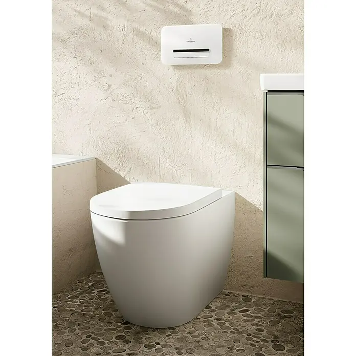 Villeroy & Boch Subway 3.0 Stand-WC - Spülrandlos, Mit schmutzabweisender Glasur, Spülform: Tief, WC Abgang: Waagerecht, Weiß Alpin - Eine moderne weiße Toilette in einem Badezimmer, mit einem passenden weißen Wandspender darüber.