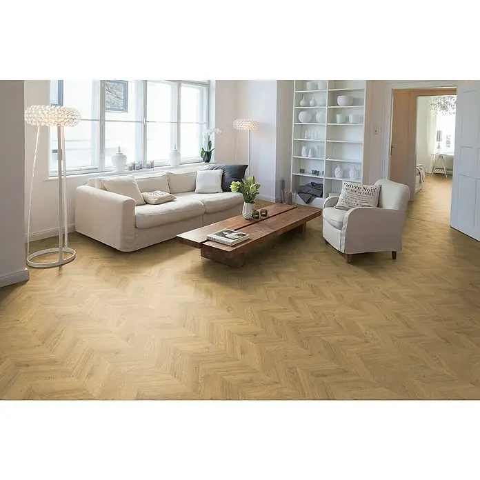 Egger Laminat NatureSense - Weinburg Eiche hell, Fischgrät, 1.292 x 327 x 8 mm - Elegantes Wohnzimmer mit einem hellen Sofa, Holztisch und einem modernen Stehlampe auf einem Parkettboden mit Fischgrätmuster.