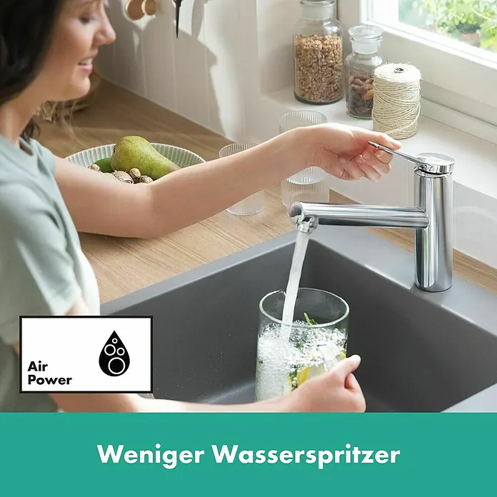 Hansgrohe Zesis M33 Spültischarmatur - Höhe: 272 mm, Chrom, Glänzend - Eine Frau füllt ein Glas an einem Chrom-Küchenhahn, der einen reduzierten Spritzwasserfluss zeigt.