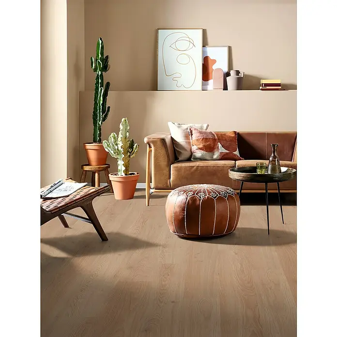 Egger Laminat NatureSense - Conway Eiche, Landhausdiele, 1.292 x 193 x 8 mm - Wohnzimmer mit braunem Ledersofa, Kaktus, Pouf und Beistelltisch auf hellem Holzboden für ein gemütliches Ambiente.