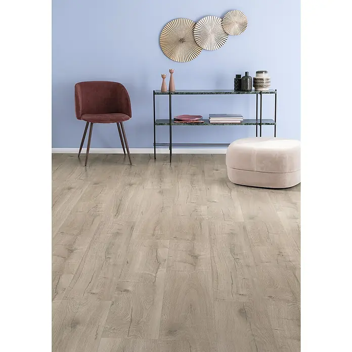 Egger Laminat NatureSense - Loja Eiche creme, Landhausdiele, 1.292 x 246 x 8 mm - Elegantes Interieur mit einem stilvollen Konsolentisch, einem bequemen Sessel und einem passenden Hocker auf einem modernen Holzboden.