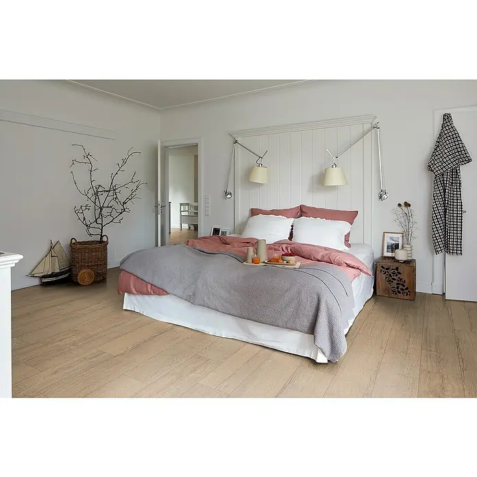 Egger Laminat NatureSense - Elva Eiche natur, Landhausdiele, 1.292 x 193 x 8 mm - Schlafzimmer mit Doppelbett, Nachttisch und Dekoration. Das helle Holzparkett verleiht dem Raum eine warme Atmosphäre.