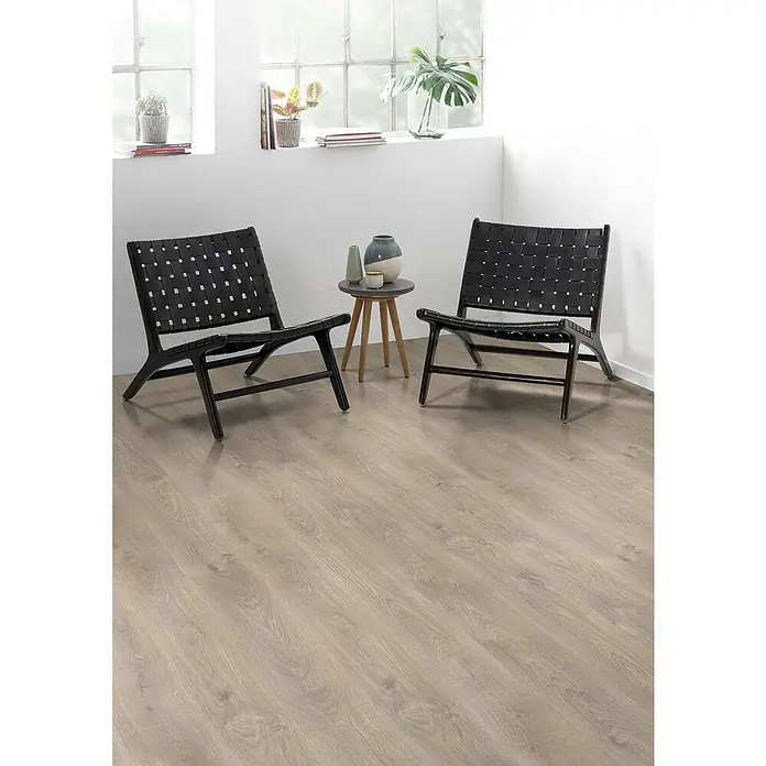 Egger Laminat NatureSense - Belfort Eiche silber, Landhausdiele, 1.292 x 193 x 7 mm - Zwei stilvolle, schwarze Korbsessel stehen auf einem hellen Holzboden. Ein Beistelltisch mit Dekoration ergänzt das moderne Ambiente.