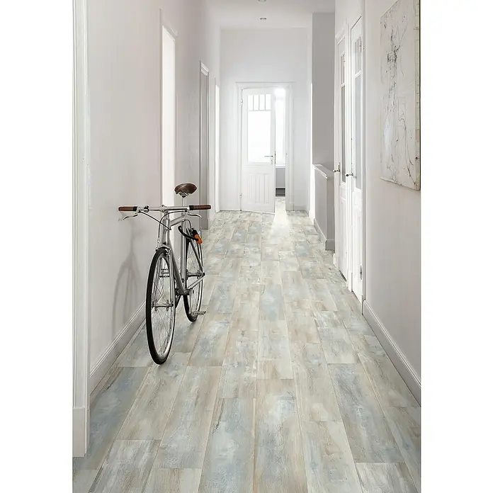 Egger Laminat NatureSense - Abergele Eiche dunkel, Landhausdiele, 1.292 x 193 x 8 mm - Ein schmaler Flur mit einem Fahrrad an der Wand und einem hellen, mehrfarbigen Holzboden, der eine gemütliche Atmosphäre schafft.