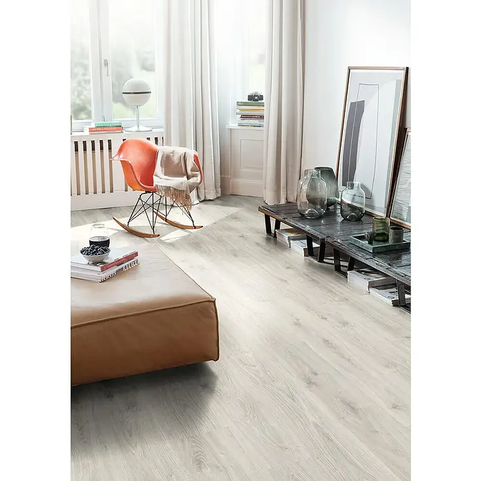 Egger Laminat NatureSense - Zermatt Eiche hell, Landhausdiele, 1.292 x 193 x 7 mm - Helles, modernes Wohnzimmer mit Laminatboden in Holzoptik, orangefarbenem Schaukelstuhl und braunem Ledersofa für ein stilvolles Ambiente.